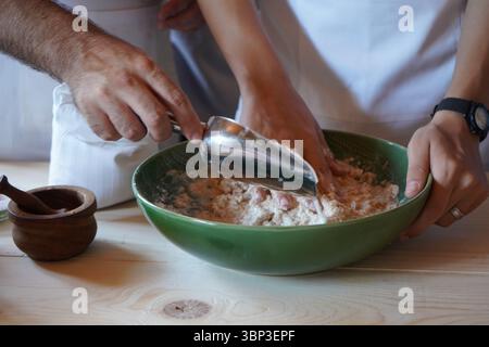 Lavorare insieme per mescolare l'impasto in una ciotola verde su un tavolo di legno: Un momento intimo e autentico di cottura e cottura da vicino. Foto Stock