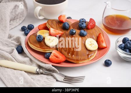 Pila di gustosi pancake con mirtilli e banana su sfondo bianco Foto Stock