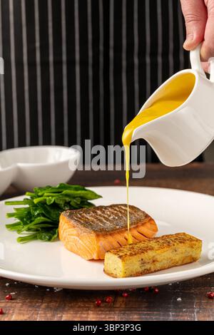 Filetto di salmone scottato servito con spinaci saltati e croquette di patate Foto Stock