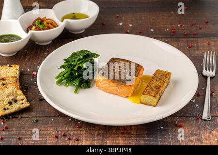 Filetto di salmone scottato servito con spinaci saltati e croquette di patate Foto Stock