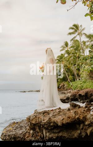 Sposa in piedi su Lava Rock con vista sull'oceano, Maui Foto Stock