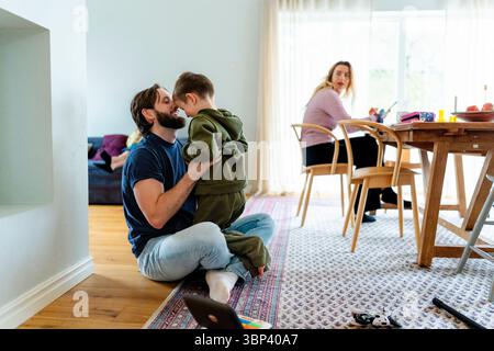 Il padre trascorre il tempo libero giocando con il figlio seduto sul pavimento di casa Foto Stock