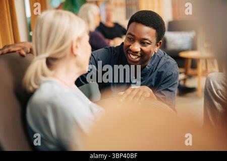Assistente sorridente che parla con una donna anziana a casa di vecchiaia Foto Stock