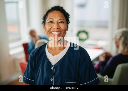 Ritratto di donna sorridente esperto di assistenza sanitaria indossando scrub medici in casa di riposo Foto Stock