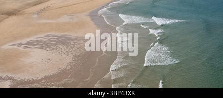 Onde che si lavano sulla sabbia alla spiaggia di Pen Hat sulla penisola di Crozon, Bretagna, Francia. Riva vuota con texture naturali e luce costiera. Foto Stock