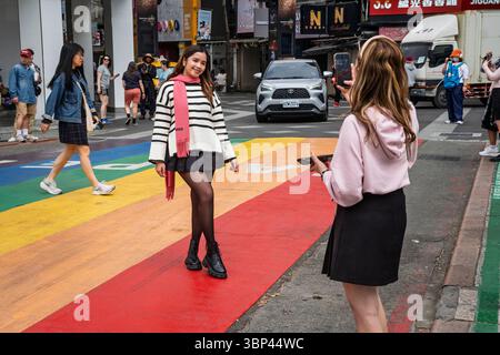 Una giovane donna che posa per una foto al Rainbow Six, la famosa balestra arcobaleno nel quartiere pedonale di Ximending, Taipei, Taiwan Foto Stock