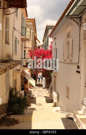 Una fotografia di una stretta strada fiancheggiata da bouganville a Nauplio o Nauplio, una città costiera situata nel Peloponneso in Grecia. È la capitale dell'unità regionale dell'Argolide e un'importante destinazione turistica. Fondata nell'antichità, la città divenne un importante porto marittimo nel Medioevo durante la Frankokratia come parte della signoria di Argo e Nauplia, inizialmente detenuta dai de la Roche dopo la quarta crociata prima di passare sotto la Repubblica di Venezia e, infine, l'Impero ottomano. La città era la seconda capitale della prima Repubblica ellenica e del Regno di Grecia, fro Foto Stock