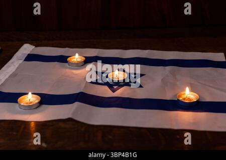 Candele commemorative che brillano su una bandiera israeliana per celebrare le festività ebraiche di Yom HaZikaron, Memorial Day e Holocaust Remembrance Day in Israele. Foto Stock