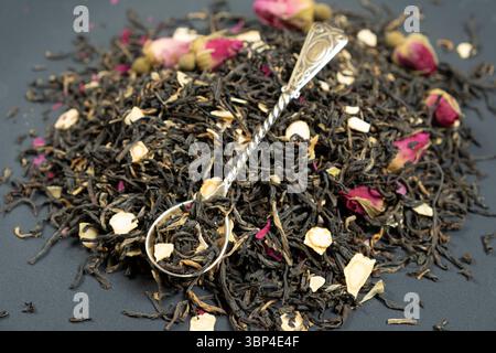 Composizione del tè nero con pezzi di ginseng e rose del tè Foto Stock