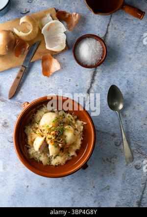 Tradizionali gnocchi di patate ceche ripieni di carne affumicata, serviti con crauti brasati e cipolle fritte in uno stile rustico di campagna. Foto Stock