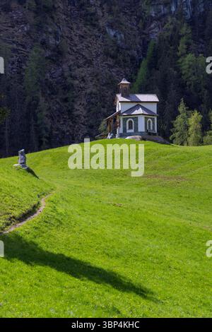 Piccola cappella bianca in piedi su una collina verde nella valle di Pragraten am Grosvenediger in Tirolo, Austria, durante una soleggiata giornata estiva Foto Stock
