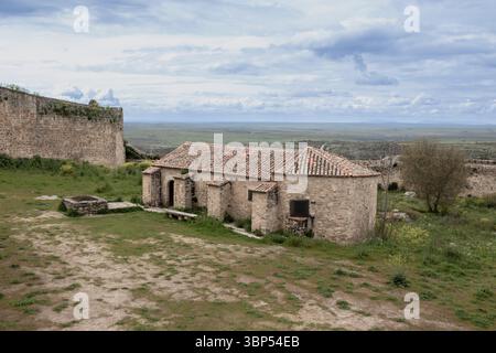 Vecchia chiesa in pietra con tetto piastrellato situata all'interno del castello di trujillo in estremadura, spagna, con vista sulla pianura Foto Stock