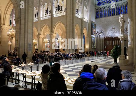 I visitatori all'interno della Cattedrale di Notre-Dame di Parigi durante una funzione religiosa con la statua della Vergine della pilla sul lato sinistro dell'altare. Parigi. Francia Foto Stock
