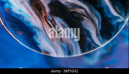 Diffusione dell'inchiostro. Particelle colorate con glitter. La texture in bronzo con bolle al neon sfocate e blu viola scorre su uno sfondo creativo astratto. Foto Stock