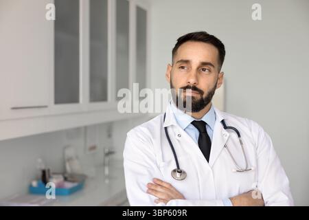Premuroso fiducioso giovane latino professionista sanitario che tiene le braccia incrociate Foto Stock