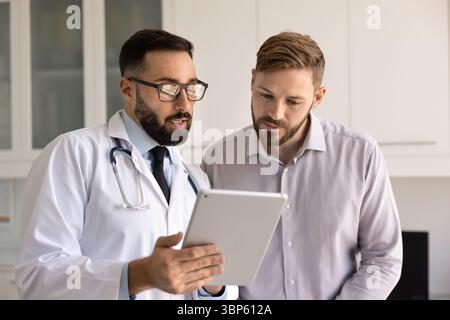 Medico serio uomo e paziente che guarda il rapporto medico Foto Stock