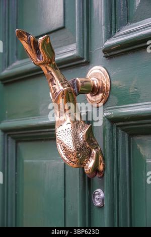 La porta in ottone a forma di pesce bussa su una porta verde, Londra Inghilterra Regno Unito Regno Unito Foto Stock