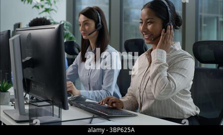 Tre persone d'affari donne caucasiche indiane multietniche, gli operatori del servizio di call center delle cuffie per uomo africano lavorano in un call center interno tramite pc Foto Stock