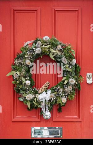 La corona decorativa di Natale è appesa su una porta d'ingresso di una casa a Kensington, Londra, Inghilterra, Regno Unito, Regno Unito Foto Stock