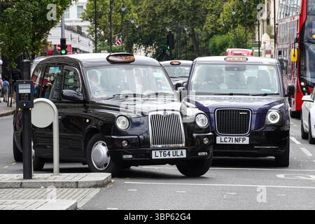 Taxi nero elettrico vecchio e nuovo a Londra Inghilterra Regno Unito Regno Unito Foto Stock