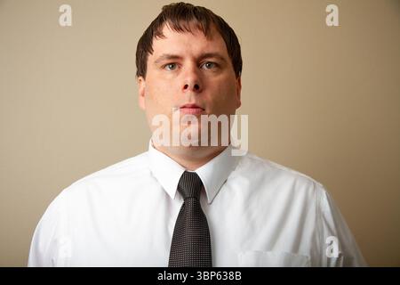 Un uomo che indossa una camicia bianca e una cravatta nera è davanti a un muro Foto Stock