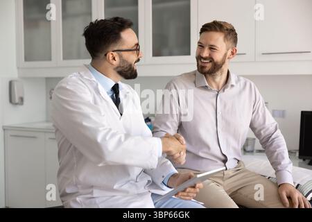 Felice medico e paziente maschio che stringe la mano Foto Stock