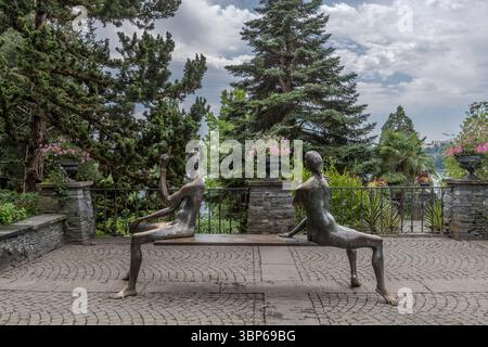 Due figure in bronzo, note come "i Sitters" di Peter Lenk, si trovano su una panchina dell'isola di Mainau vicino Costanza, in Germania. Una figura punta il dito in lontananza, mentre l'altra gode della pittoresca vista sul lago di Costanza. Questa installazione d'arte invita i visitatori a soffermarsi e contemplare l'ambiente circostante Foto Stock