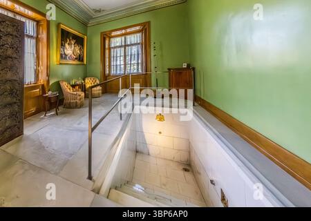 Il bagno storico nel castello di Arenenberg a Salenstein, Thurgau, Svizzera. La camera dispone di un bagno romano incassato con un emblema di aquila napoleonica, circondato da mobili eleganti e da un dipinto classico. Questa area privata era un tempo utilizzata da Hortense de Beauharnais, regina d'Olanda e madre di Napoleone III, e riflette lo stile di vita lussuoso dell'epoca Foto Stock