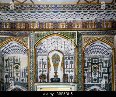 Intricate decorazioni murali con motivi floreali colorati e disegni geometrici in un ambiente architettonico decorato. Foto Stock