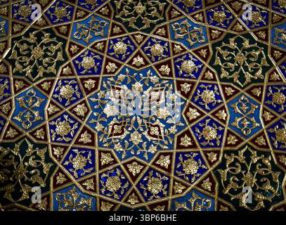 Un motivo geometrico vivace e intricato caratterizzato da colori blu, oro e marrone. Il design presenta motivi floreali e stellari dettagliati, creando una me Foto Stock