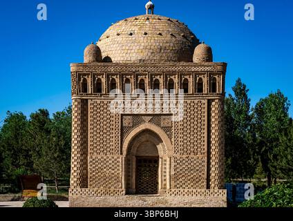 Un edificio storico splendidamente disegnato con intricati mattoni e una cupola, circondato da lussureggiante vegetazione sotto un cielo azzurro. Foto Stock