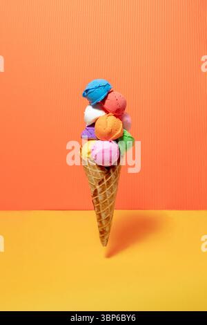 Gelato multicolore con cono gelato su sfondo giallo e arancione. Colori vivaci Foto Stock