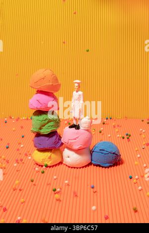 Palline per gelato multicolore e giocattolo dello chef su sfondo giallo e arancione. Colori vivaci Foto Stock