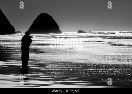 Arch Cape, Oregon - 26 novembre 2015: Un fotografo cattura la bellezza panoramica della costa dell'Oregon, incorniciando le iconiche formazioni rocciose. Foto Stock