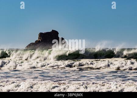 Arch Cape, Oregon - 26 novembre 2015: Una potente onda si schianta vicino a un affioramento roccioso, mostrando la bellezza e l'energia grezza dell'Oceano Pacifico. Foto Stock