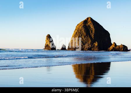 Haystack Rocks, Cannon Beach, Oregon - 27 novembre 2015: Le onde si infrangono dolcemente sulla riva vicino all'iconica Haystack Rock, una popolare destinazione turistica. Foto Stock