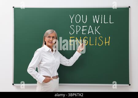 Insegnante che indica il testo parlerà inglese su una lavagna verde. Corso di lingua Foto Stock