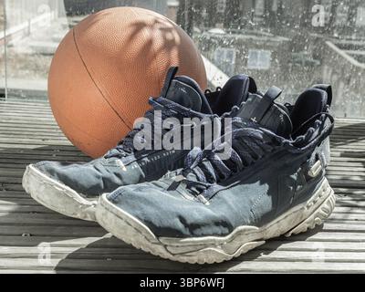Londra, Regno Unito - 17 maggio 2025 - scarpe da pallacanestro e palla da basket vengono posizionate sul balcone, dopo l'allenamento da basket. Usala come Wal Foto Stock