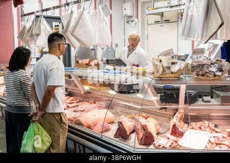 Firenze, Italia - 10 maggio 2025: I clienti interagiscono con un macellaio in un banco di carne del mercato centrale Foto Stock
