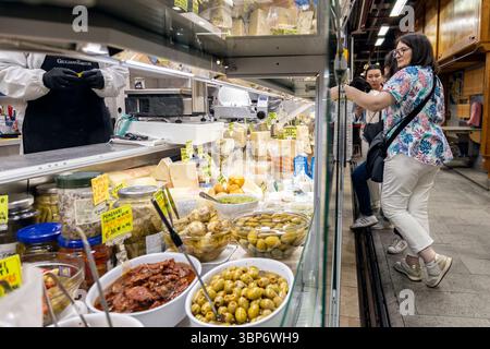 Firenze, Italia - 10 maggio 2025: Gli amanti dello shopping presso un banco gastronomico con formaggi, olive e verdure conservate al mercato centrale Foto Stock