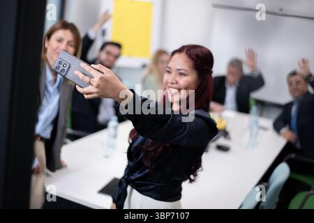 Un allegro gruppo di colleghi si riunisce intorno a un tavolo in un moderno ambiente di ufficio, condividendo un momento di incontro informale e divertimento con un gruppo Foto Stock