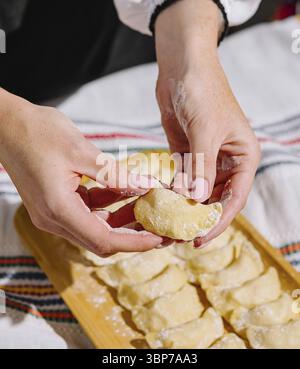 Cibo, immagine ravvicinata di mani che preparano gnocchi fatti in casa su una tavola di legno Foto Stock