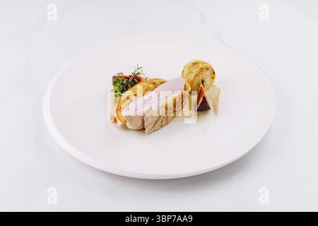 Cibo: Delizioso lombo di maiale arrosto servito con fichi, patate e salsa su un piatto bianco Foto Stock