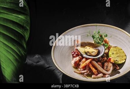 Cibo, Un piatto di pesce ben organizzato con gamberi, polpi e cozze, accentuato con lime e guarnito con erbe fresche. Questo visivamente Foto Stock