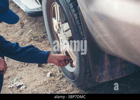 Il meccanico esegue il controllo degli pneumatici per auto all'aperto in loco per i servizi di centri mobili automobilistici. Controllo della riparazione in officina da parte di un tecnico t Foto Stock