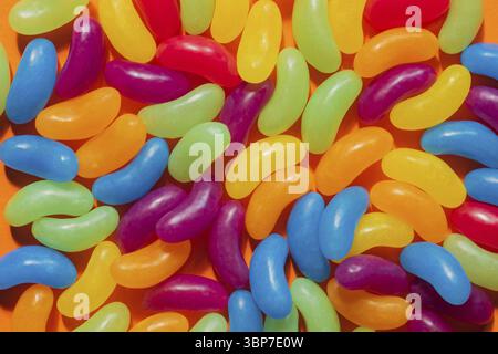 Jelly Beans assortiti bordo con copyspace su sfondo arancione Foto Stock