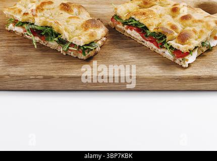 Cibo, panini italiani a fette con verdure e formaggio su un tagliere, isolati su sfondo bianco Foto Stock