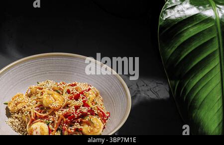 Cibo, questo piatto presenta un vivace gamberetto fritto con verdure colorate e una spolverata di semi di sesamo. Il cibo è allestito in modo elegante Foto Stock