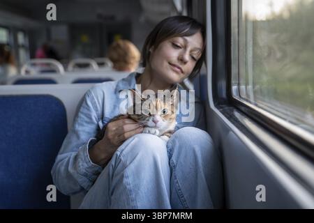 Vacanza con animali domestici. Cat che viaggia in treno con il suo proprietario. Kitty si siede su giri di donna, sentendosi stressato e ansioso mentre viaggia in treno per i primi Foto Stock