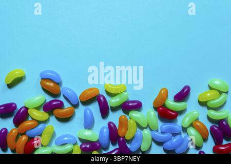 Jelly Beans assortiti bordo con copyspace su sfondo blu Foto Stock